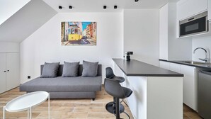 A modern kitchen with a dining area, a sofa, and a painting on the wall.