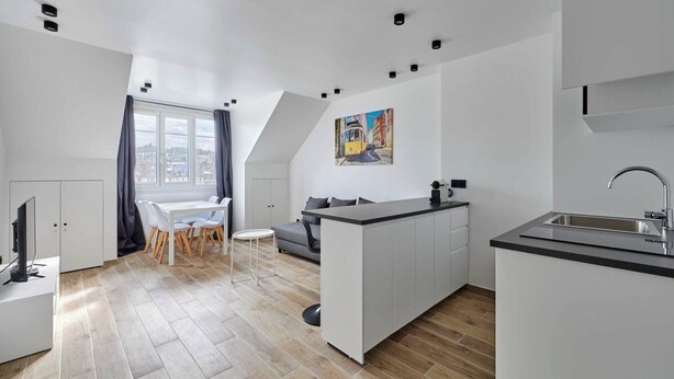 A modern apartment with a dining area, kitchenette, and a large window offering a city view.