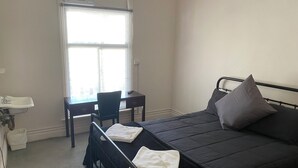 A bedroom with a bed, a desk, and a chair. - Culcairn Hotel (Culcairn)