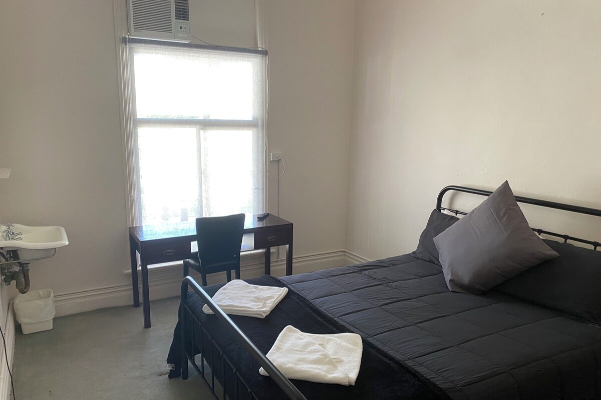 A bedroom with a bed, a desk, and a chair.