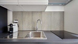 A modern kitchen with a stainless steel sink, a built-in oven, and a compact microwave.