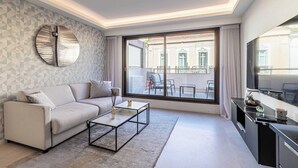 Un salon moderne avec un canapé, une table basse et une grande fenêtre donnant sur l’extérieur.