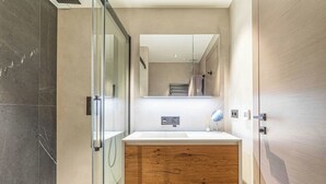 Une salle de bain moderne avec une douche à parois de verre, un meuble-lavabo en bois et un grand miroir.