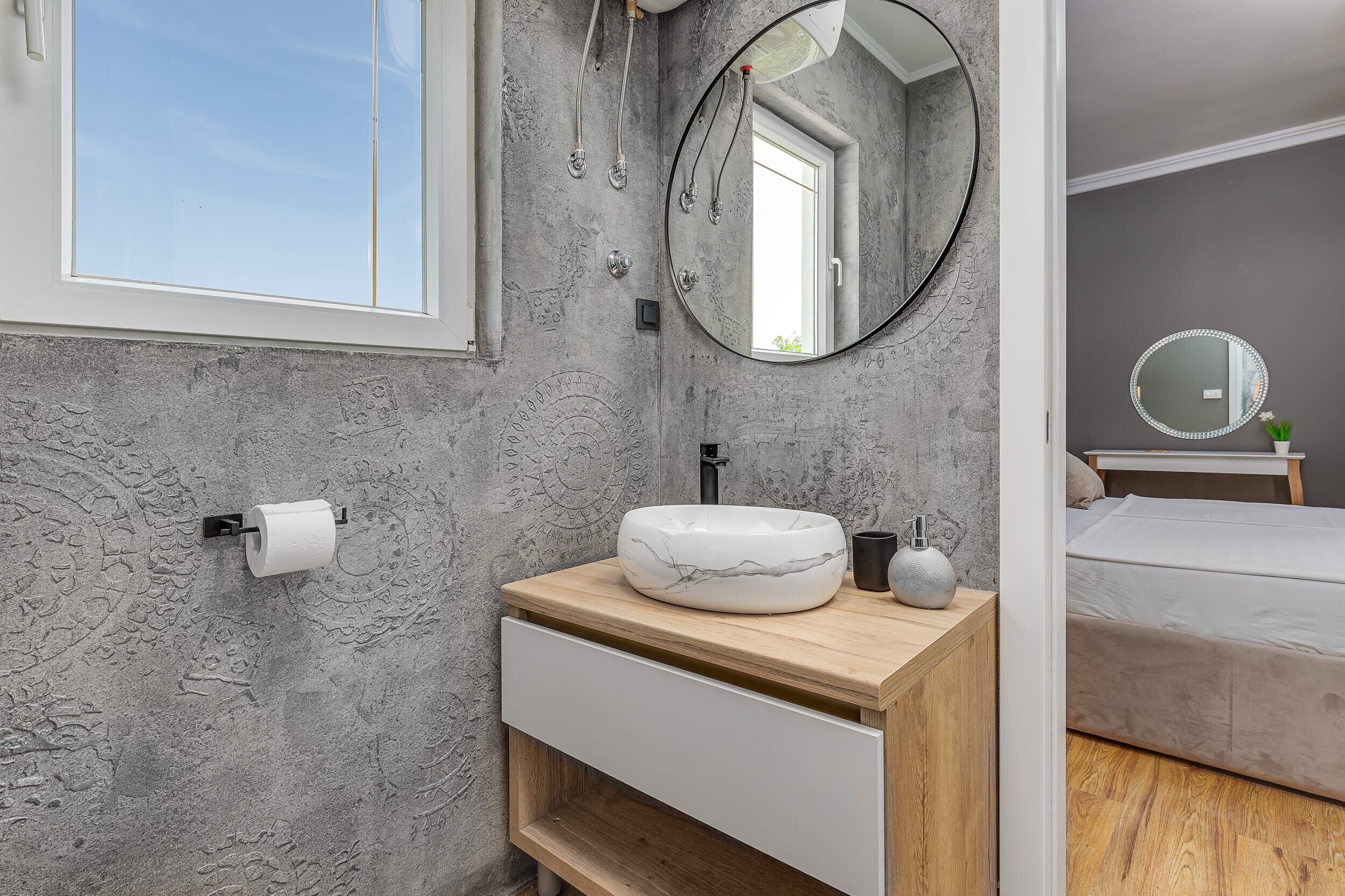 A bathroom with a marble sink, a mirror, and a toilet paper holder.