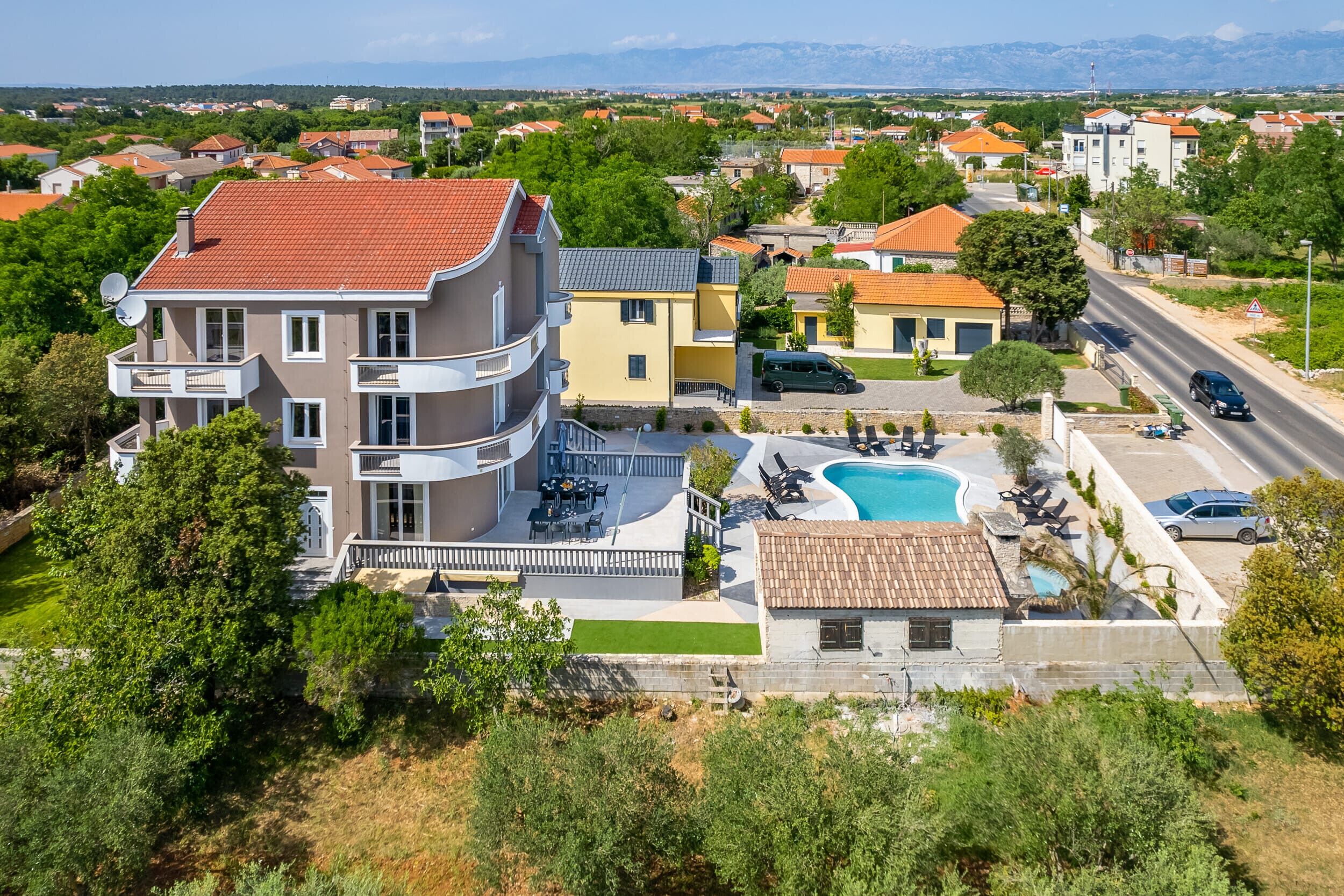 Ein mehrstöckiges Wohnhaus mit Schwimmbad, Außenbereich zum Sitzen und Blick auf die umliegende Nachbarschaft.
