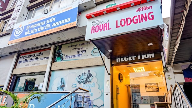 Un hôtel appelé « Royal Lodging », avec une enseigne dans une langue étrangère, un escalier et un mur recouvert de publicités.