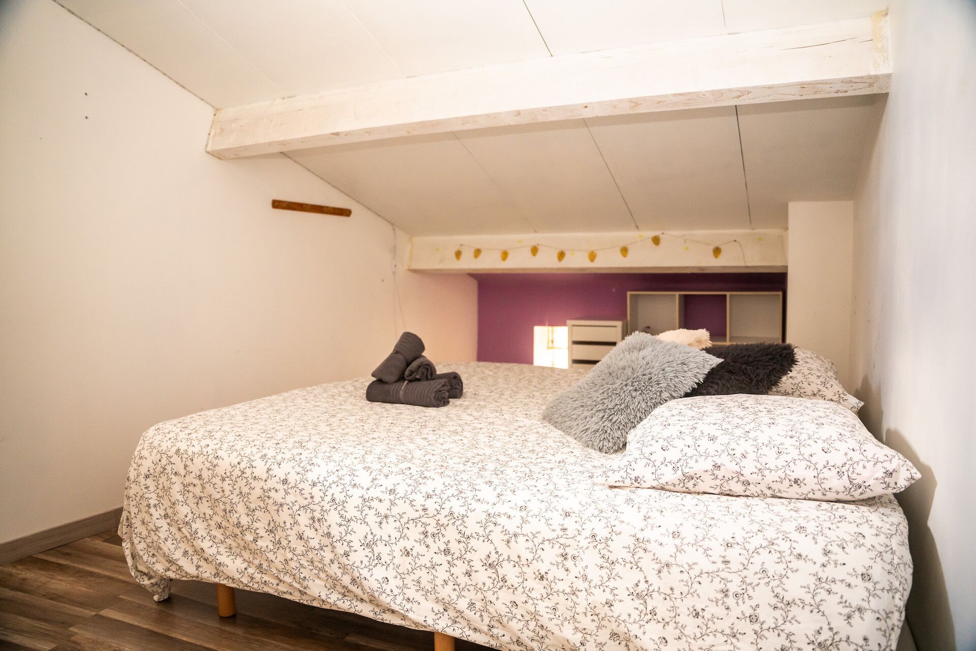 Une chambre à coucher avec un lit, des oreillers et une couverture pliée.