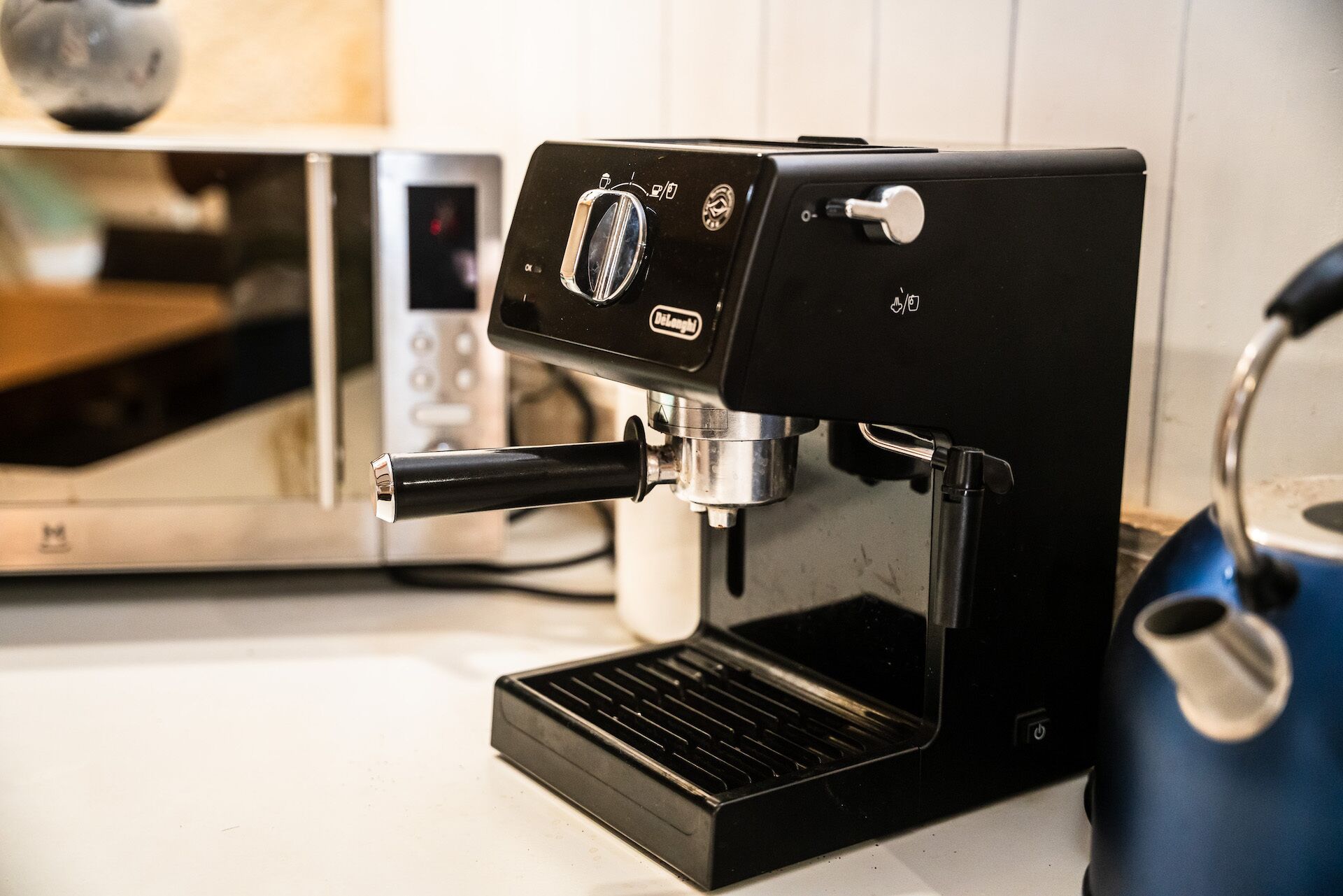 Une machine à expresso noire, dotée d’un écran numérique et d’une buse vapeur, est posée sur un plan de travail de cuisine.