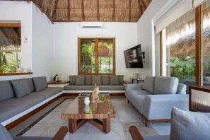 A modern living room with a sofa set, a coffee table, and a TV mounted on the wall.