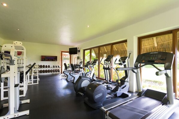 Une salle de sport équipée de tapis de course, de vélos elliptiques et de matériel de musculation.
