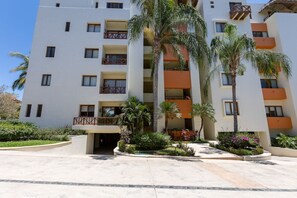 A multi-story hotel with balconies, palm trees, and a landscaped garden.