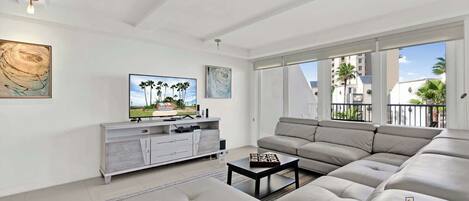 A modern living room with a large sectional sofa, a flat-screen TV, and a minimalist white console.