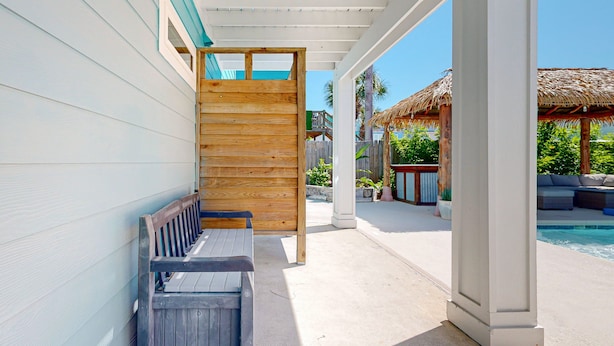 A covered outdoor area with a wooden bench, a pool, and a thatched-roof structure. - Private Pool, Palapa, Golf Cart Access (Port Aransas)