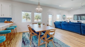 A modern kitchen with white cabinetry, a wooden dining table, and blue bar stools. - Private Pool, Palapa, Golf Cart Access (Port Aransas)