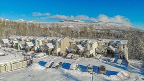 A snow-covered residential area with multiple houses and parked cars.