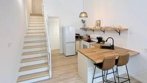 A small kitchen with a wooden island, a refrigerator, a microwave, and a hanging light fixture.