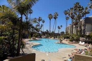 Relax by the resort's large oval pool surrounded by tall palm trees and lounge chairs.