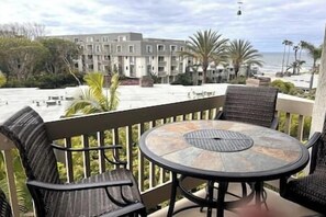 Relax in this outdoor seating area with a round table and four chairs, offering a view of the beach and ocean.