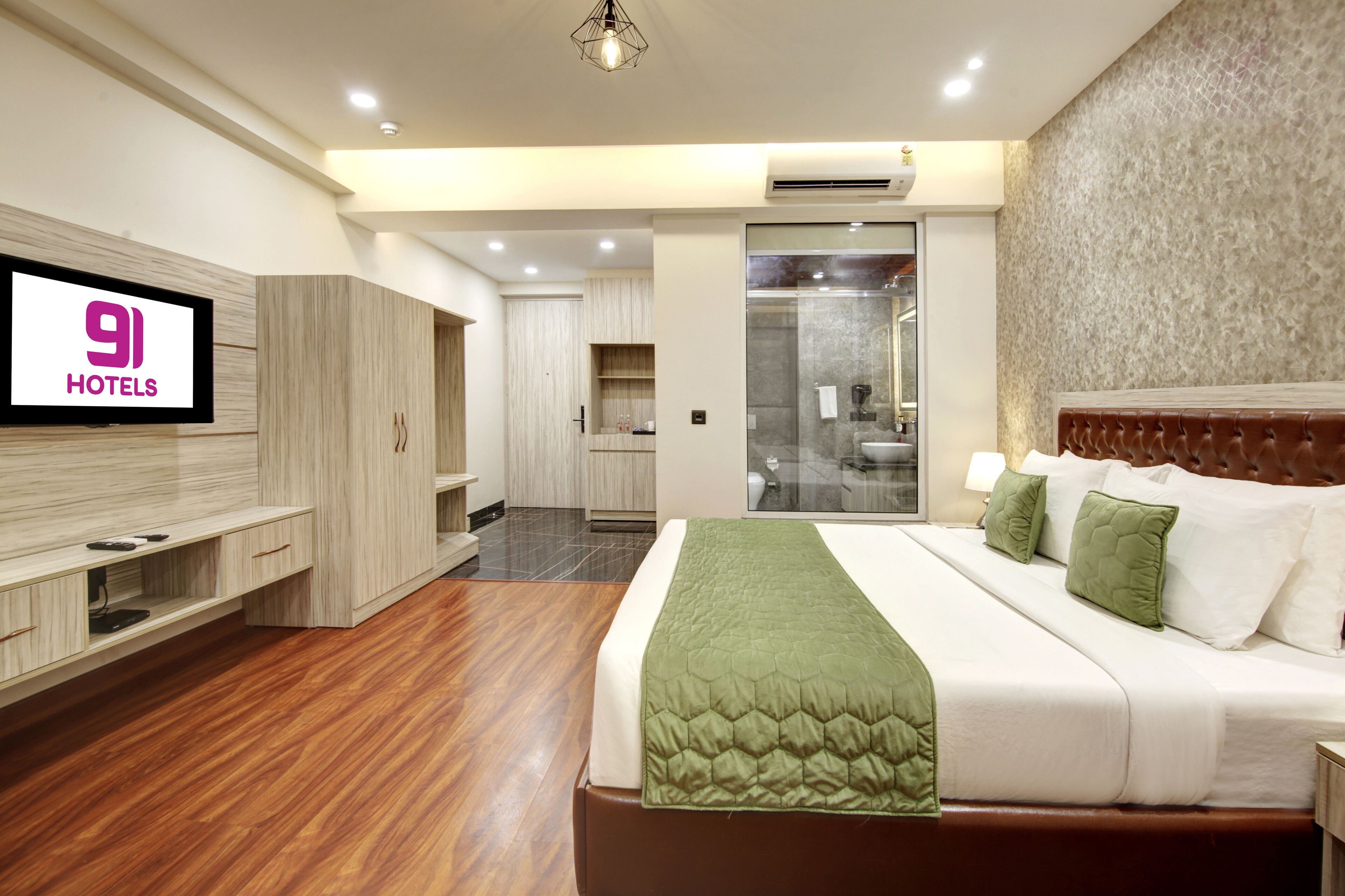 A hotel room with a bed, a TV, a wardrobe, and a bathroom visible through an open door.