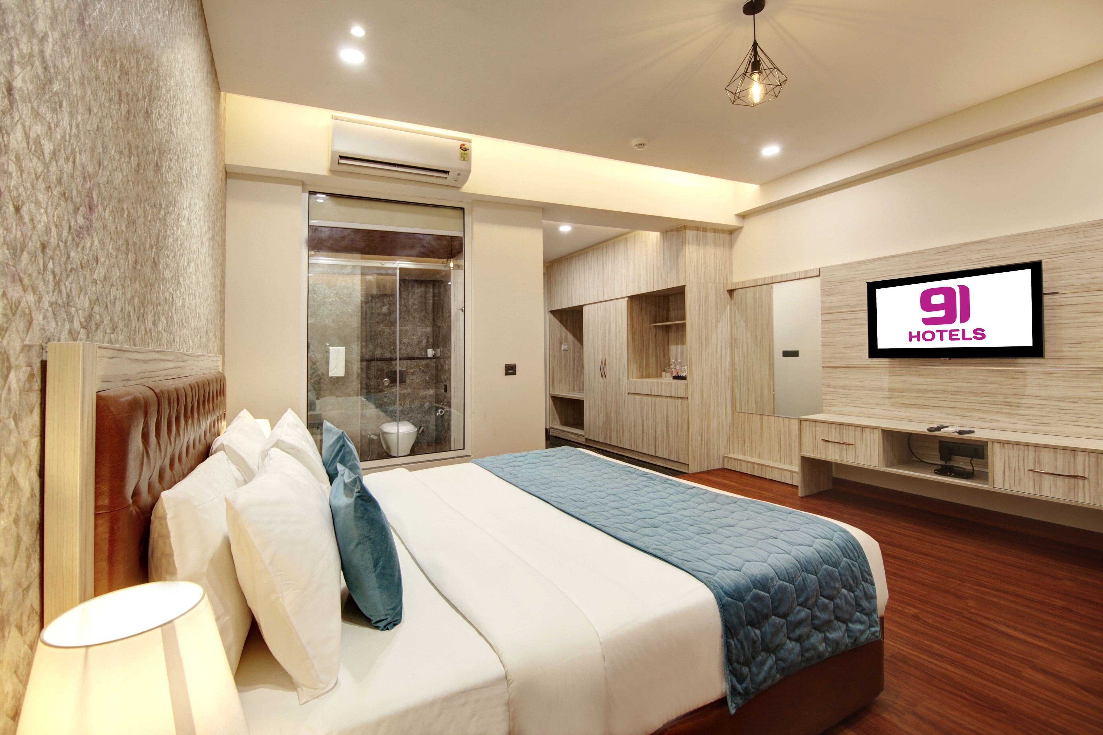 Une chambre d’hôtel moderne équipée d’un grand lit, d’une télévision, d’une armoire et d’un espace douche.
