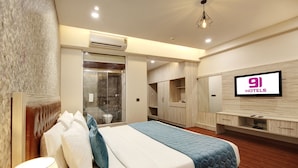 Une chambre d’hôtel moderne équipée d’un grand lit, d’une télévision, d’une armoire et d’un espace douche.