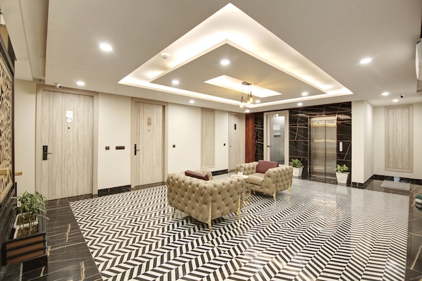 A modern lobby with a geometric patterned floor, plush seating, and a central light fixture.