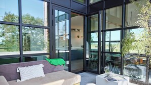 Un salon moderne avec un canapé, une table basse et une vue sur un espace patio extérieur.