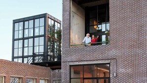 Un bâtiment à deux étages avec une façade en briques, un balcon et un trampoline au premier plan.