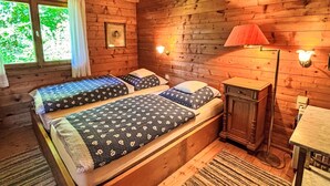 Une chambre dans un chalet en bois, avec un lit, des lampes de chevet et une fenêtre avec des rideaux.