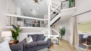 A spacious living area with a grey sofa, a coffee table, and a staircase leading to an upper level. - Location Location! Steps to beach, parking (San Diego)