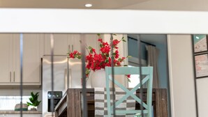 A modern kitchen with white cabinets, a wooden dining table, and a chair with a checkered pattern. - Location Location! Steps to beach, parking (San Diego)