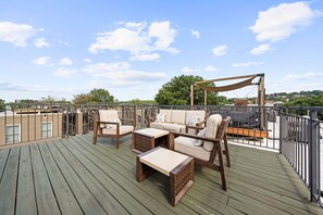A rooftop deck with outdoor furniture, a pergola, and a view of the cityscape.