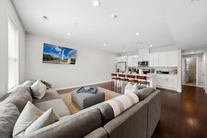Una sala de estar moderna con un sofá gris, una mesa de centro y un cuadro de un paisaje.