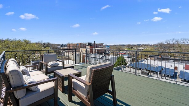 A rooftop deck with outdoor furniture, a view of the cityscape, and solar panels.