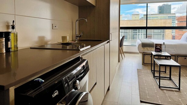 A modern kitchen with a built-in stove, a sink, and a window overlooking a cityscape.