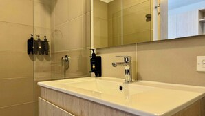 A modern bathroom with a large mirror, a white sink, and a wooden vanity.