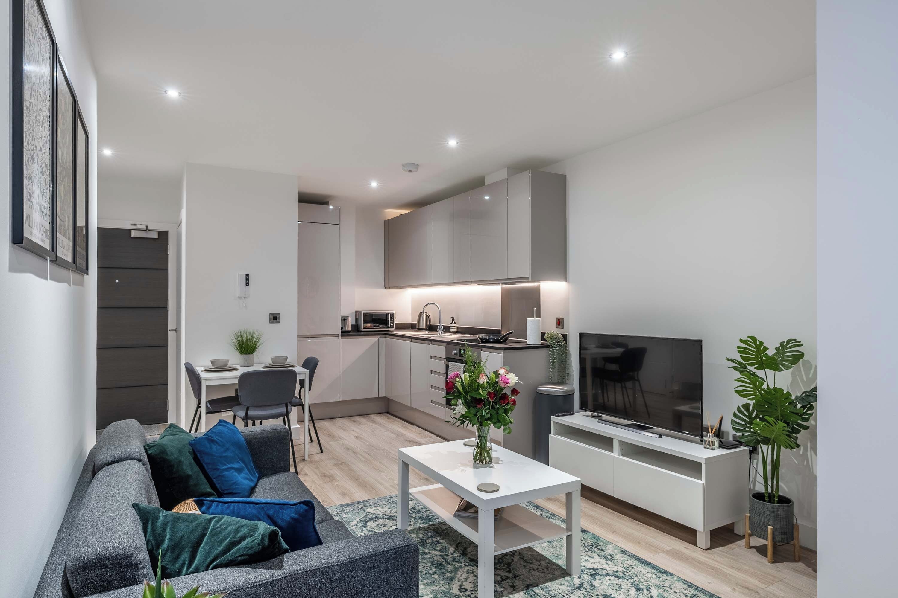 A modern living room with a grey sofa, a white coffee table, and a flat-screen TV.