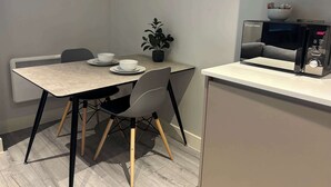 Eine kleine Küchenzeile mit einer Mikrowelle, einer kleinen Schüssel und einem Blumentopf auf einem Tisch.