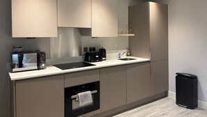 Eine moderne Küche mit eingebauten Geräten, einer Spüle und einem Mülleimer.