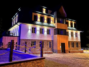 A multi-story building with a stone facade and wooden accents, featuring a stone staircase and a rope barrier in front.