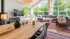 Amplia sala de estar con una gran mesa de madera, un sofá y un televisor.