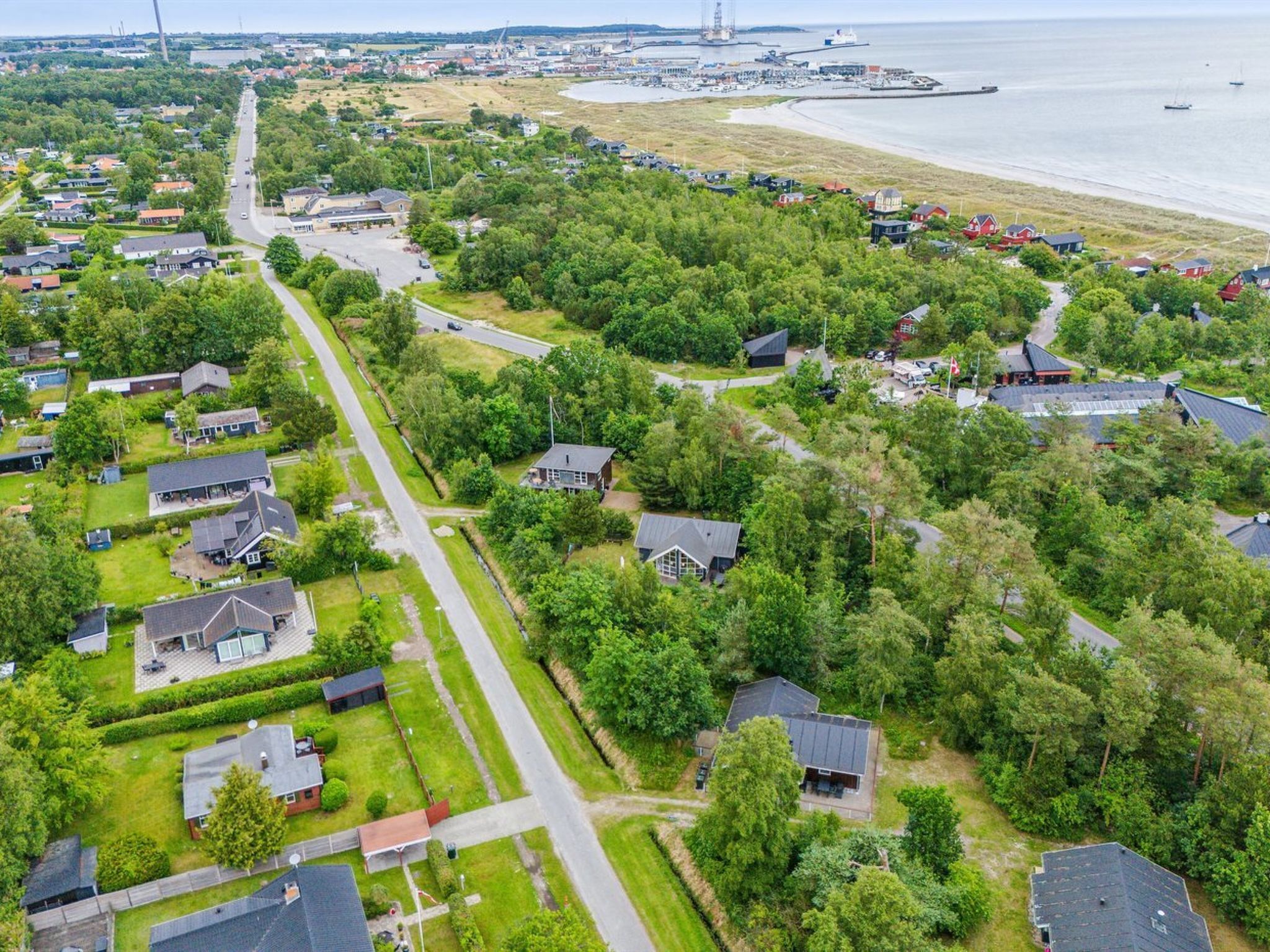An aerial view of a residential area with houses, roads, and a beach.