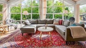 Una habitación espaciosa con un amplio sofá modular, una mesa de centro redonda y una alfombra colorida con motivos.