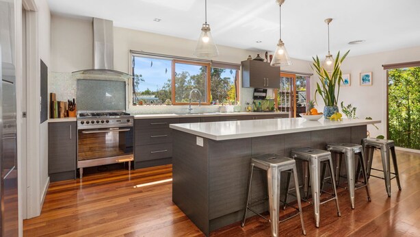 A modern kitchen with a large island, stainless steel appliances, and bar stools.