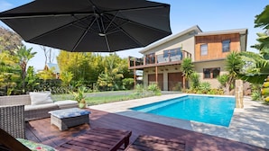 A modern house with a swimming pool, outdoor furniture, and lush greenery.