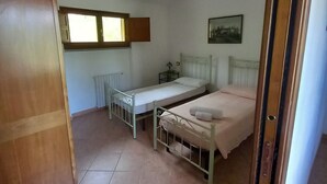 Une chambre avec deux lits, un radiateur, une fenêtre et un lustre.