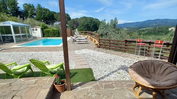 Un espace extérieur abrité comprenant une piscine, des chaises longues et une vue sur le paysage.