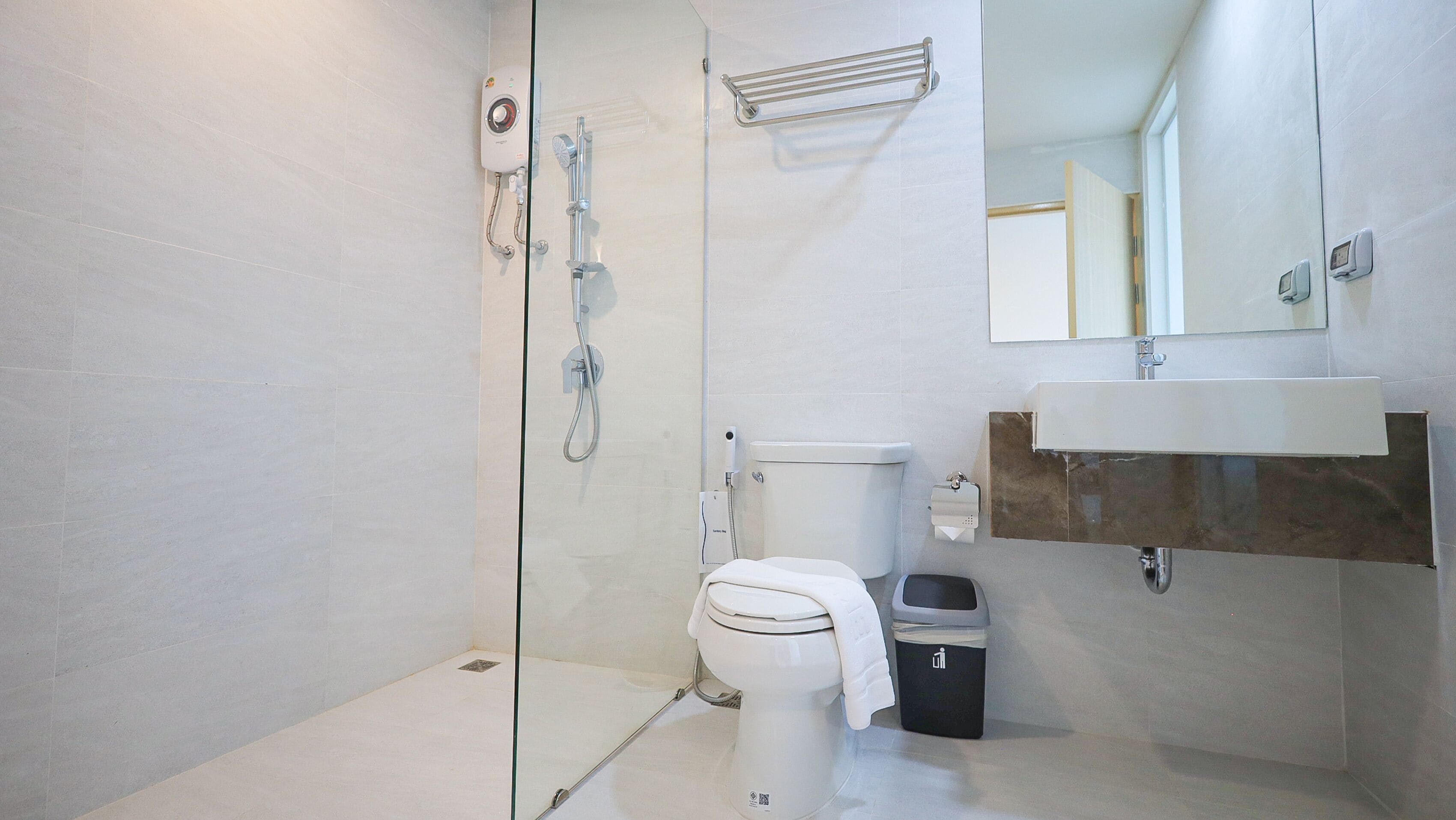 A modern bathroom with a glass-enclosed shower, a toilet, a bidet, and a sink with a marble countertop.