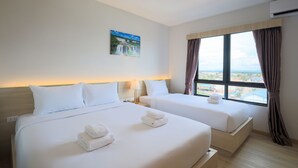 Habitación de hotel con dos camas, un cuadro en la pared, una ventana con cortinas y vistas a la ciudad.