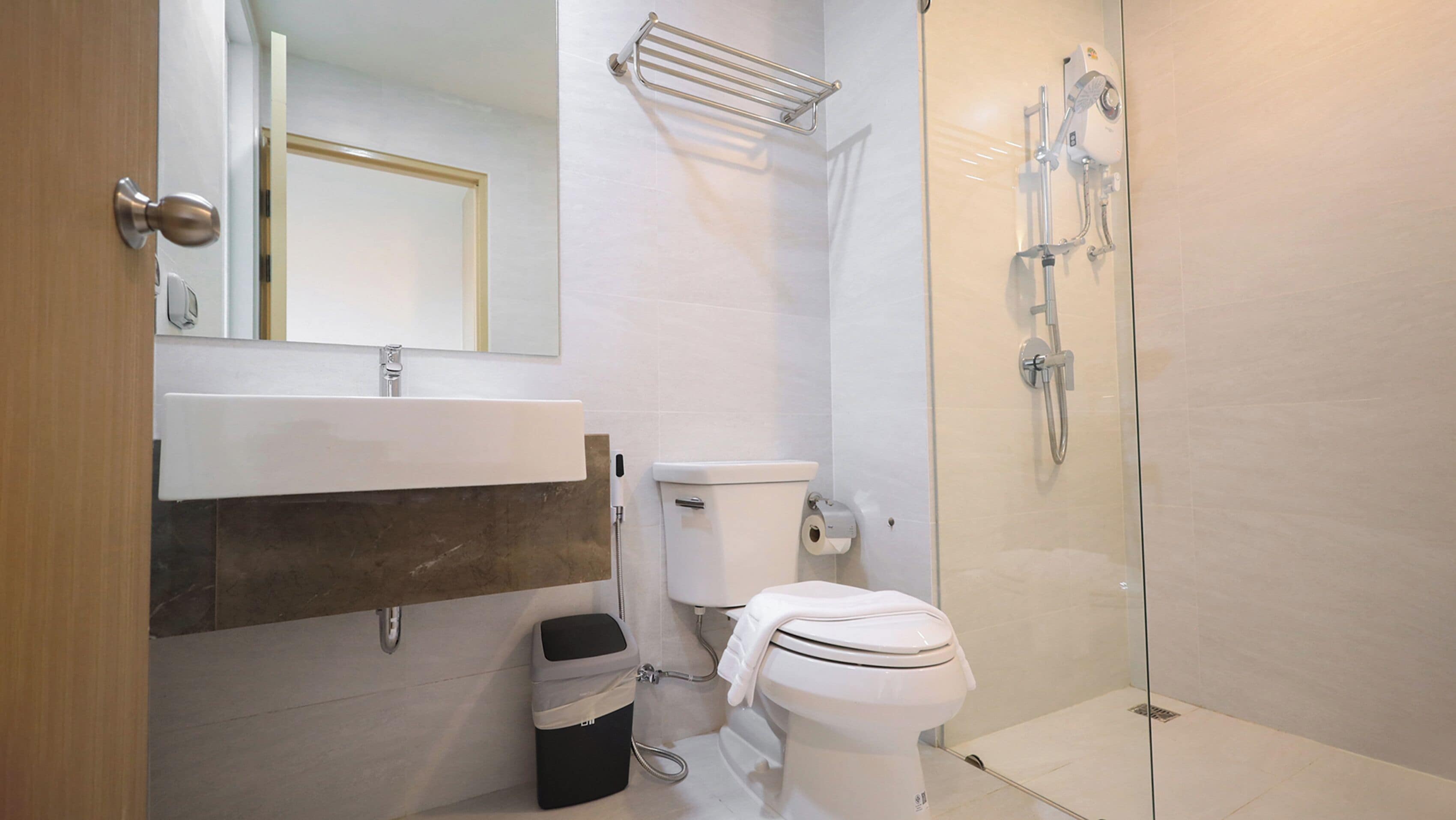 Et moderne badeværelse med vask, toilet og brusekabine med glasvægge.